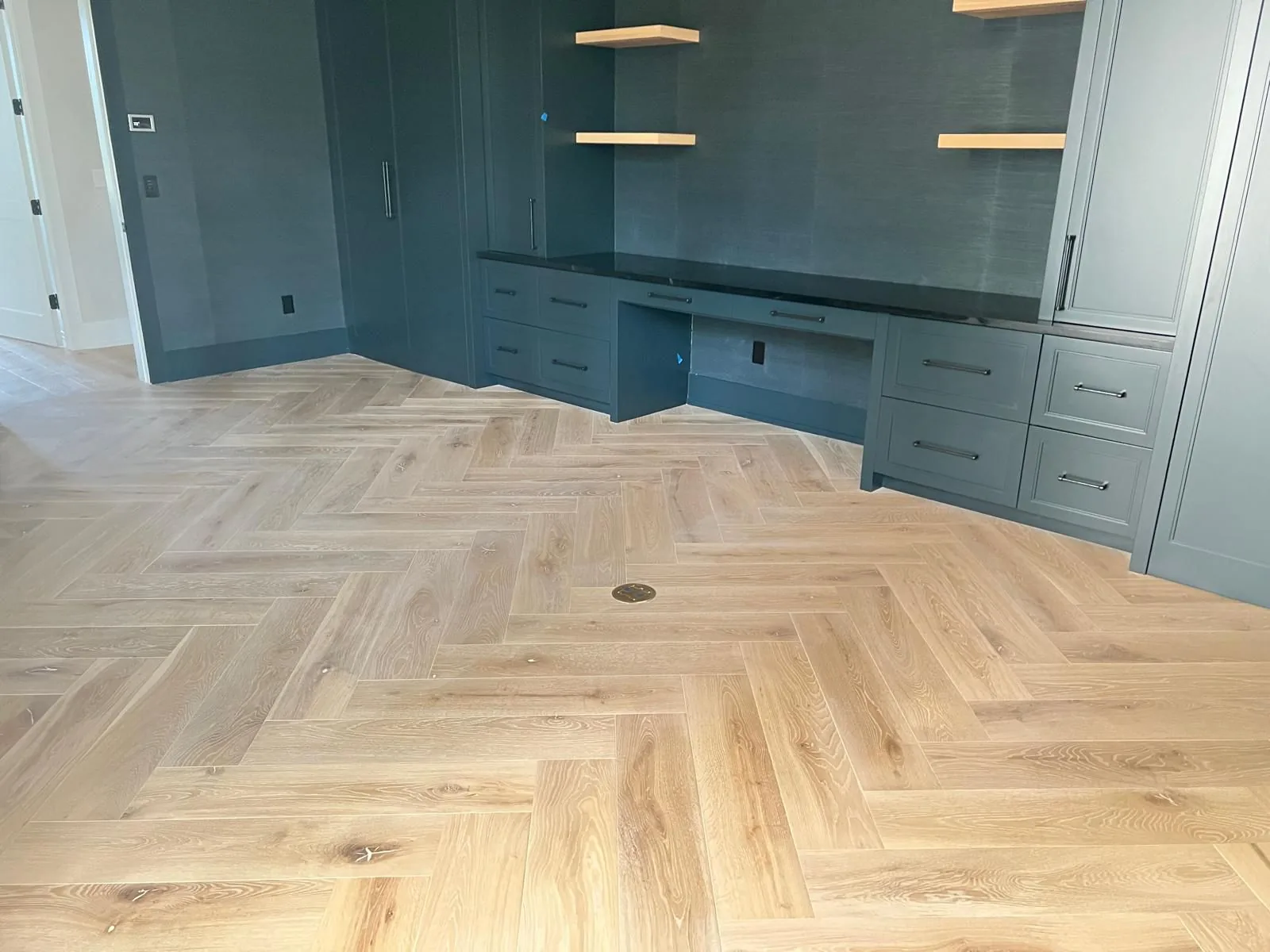 Light herringbone hardwood floor in a room with built-in cabinetry