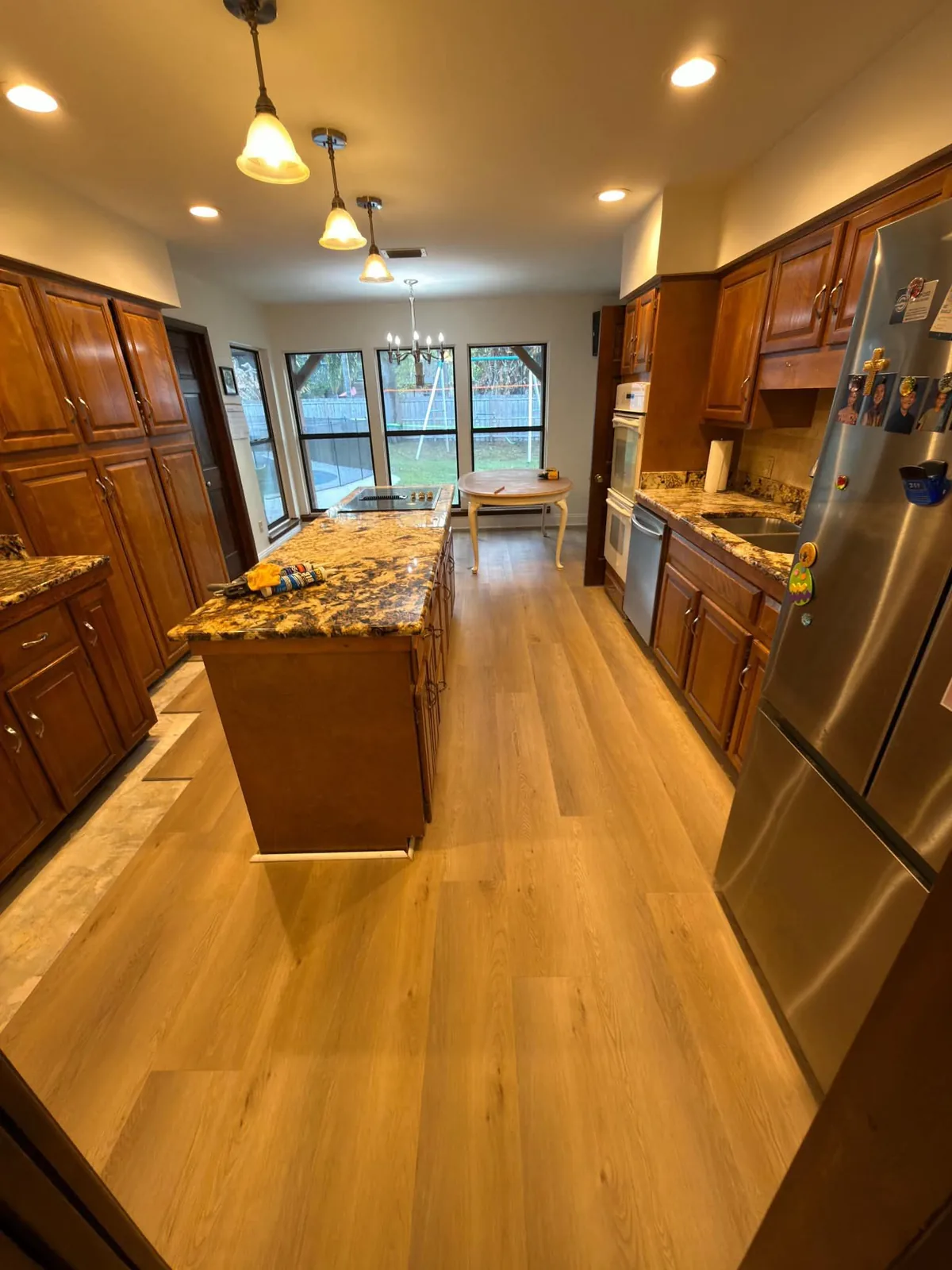 Hardwood flooring running through a kitchen with a granite island