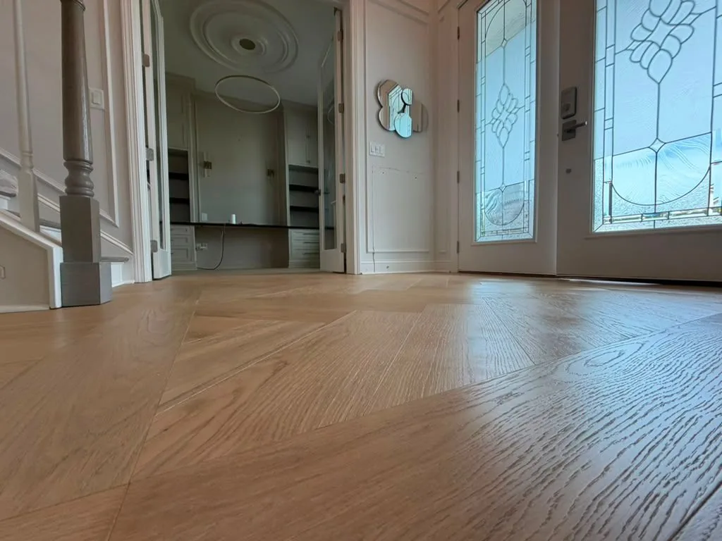 Wide oak plank flooring in an entry with a stained glass door