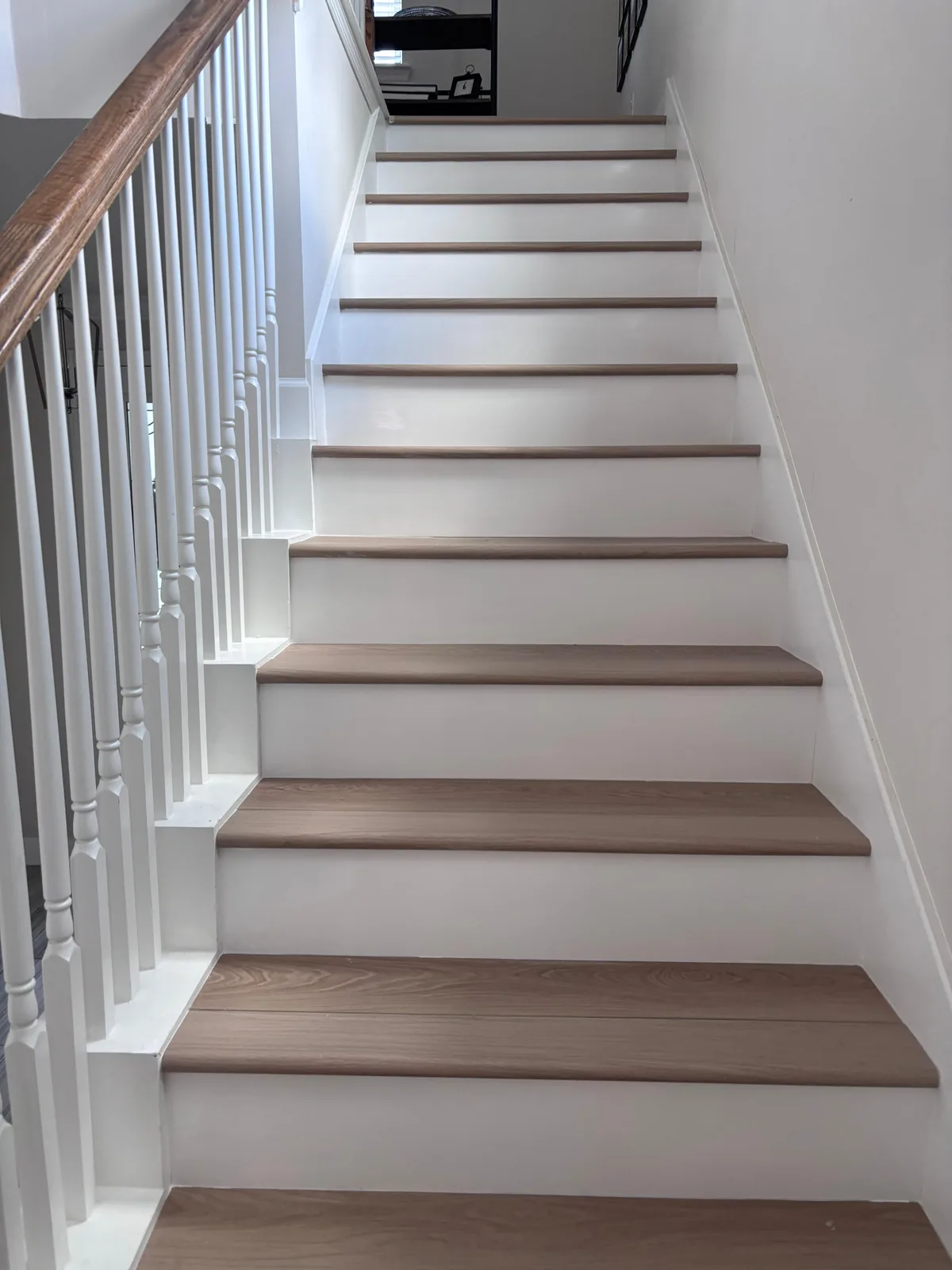 Hardwood stair treads with painted white risers and a wood rail