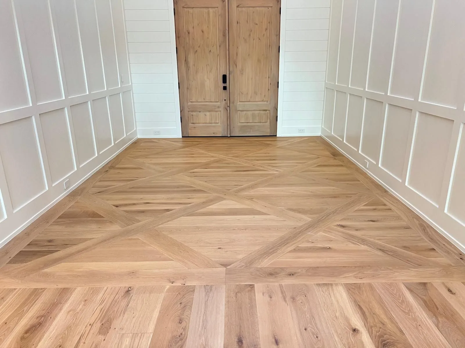 Finished hardwood floor with a parquet border in a bright entry room