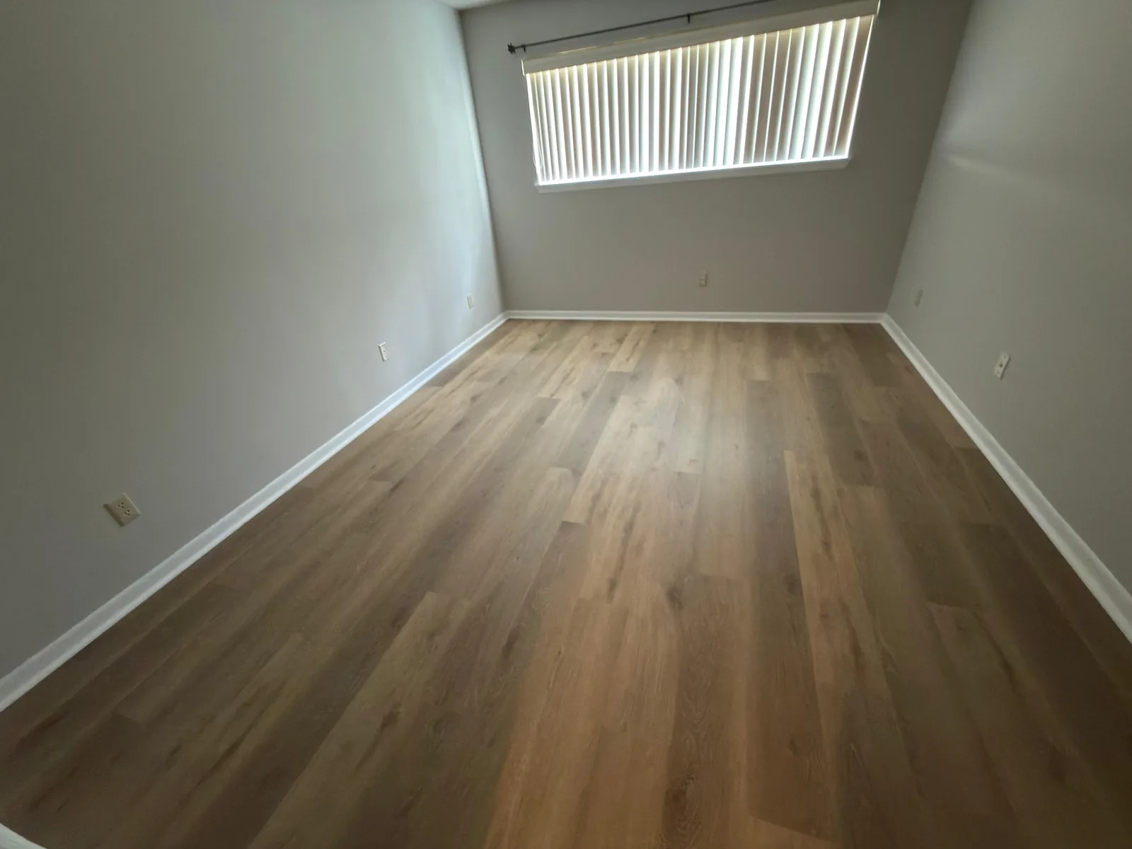 Luxury vinyl plank flooring in a bedroom with vertical blinds