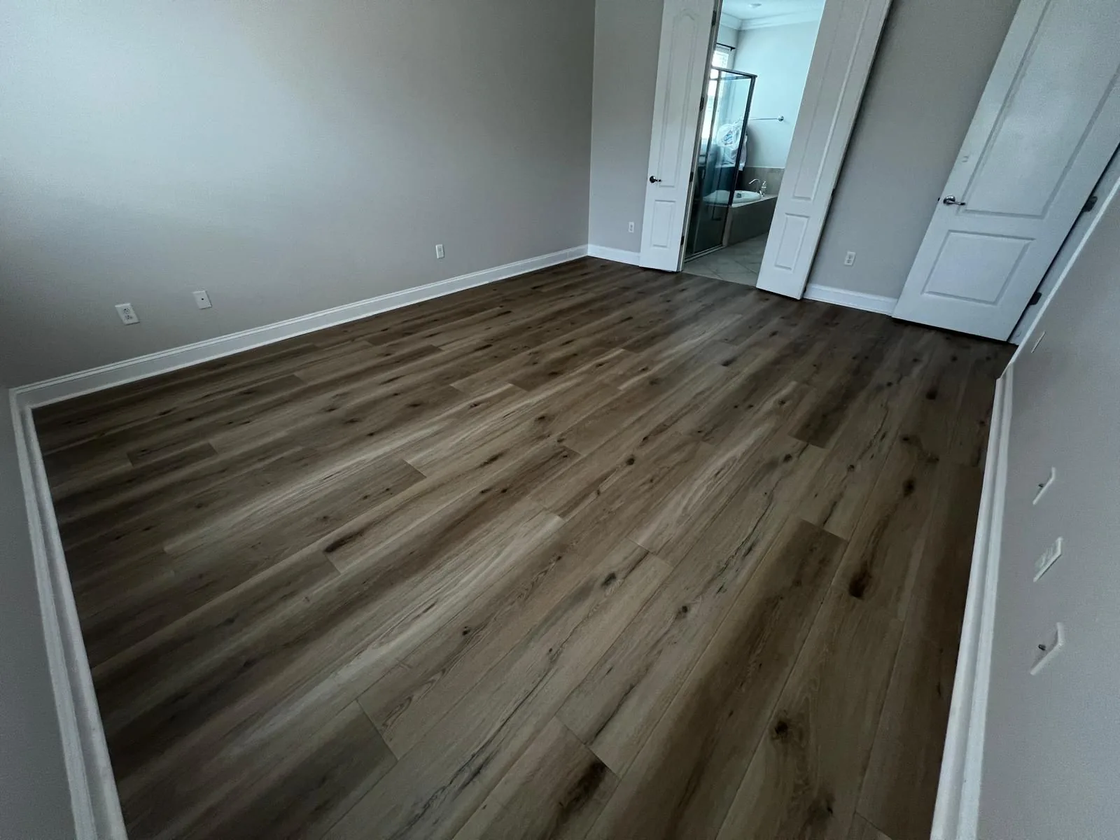 Grey luxury vinyl plank flooring in an empty bedroom