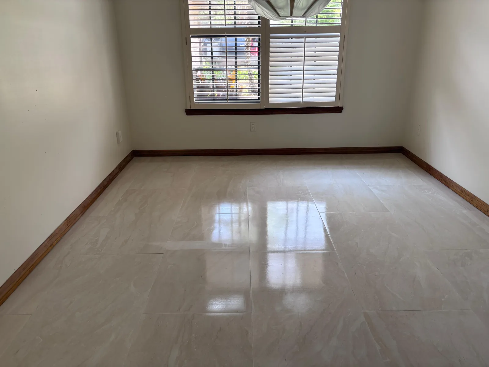 Polished porcelain tile floor in a room with a shuttered window